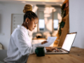 Business woman using a laptop while holding paper