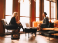 Female lawyers discussing while sitting by window at office