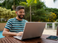 Man working on laptop near pool at a hotel